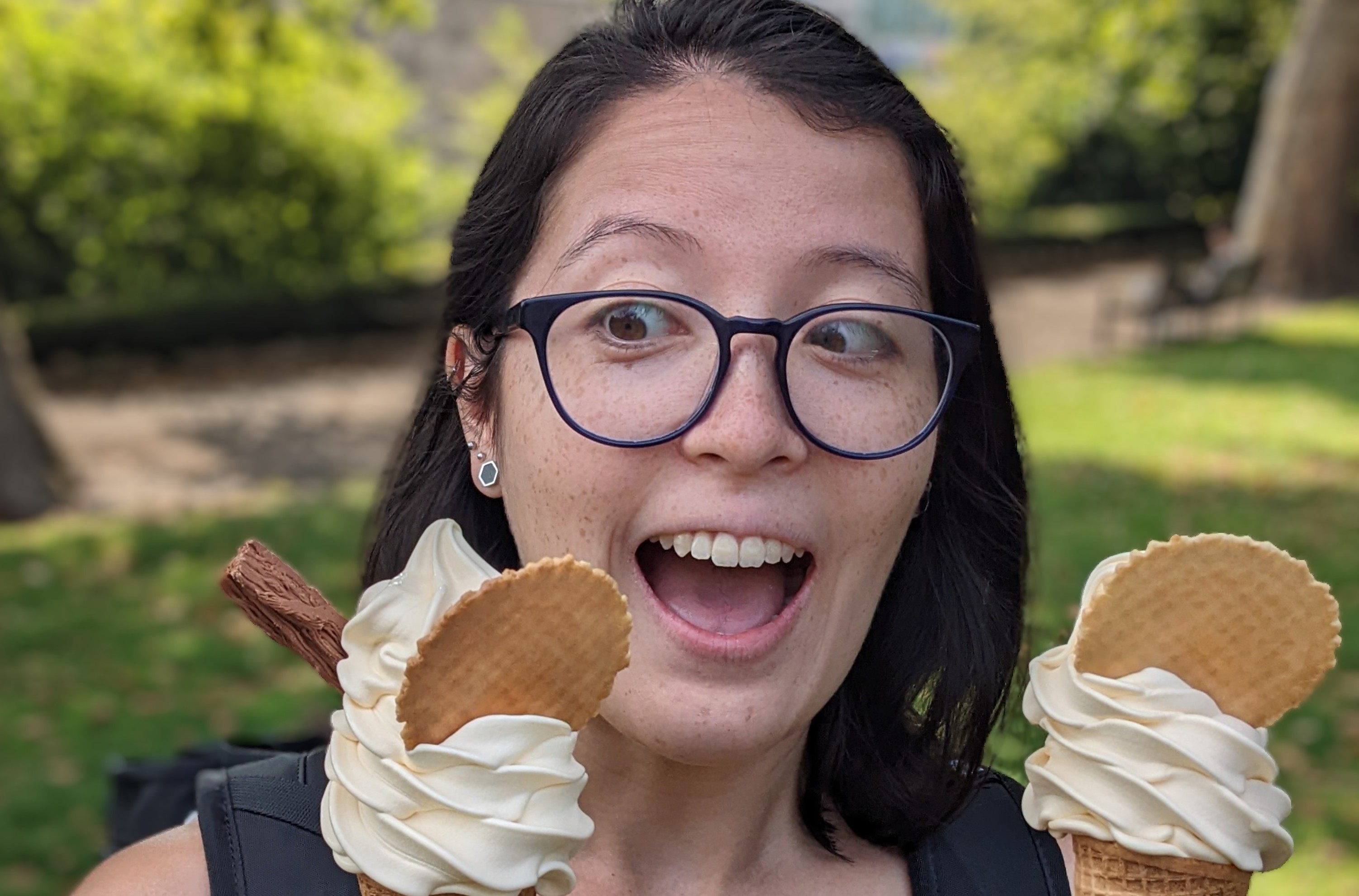 female with short dark brown hair and glasses looking excitedly at an impressive ice cream cone